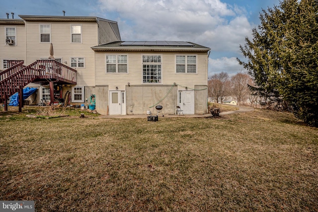 rear view of house with solar panels, a yard, stairway, and a wooden deck