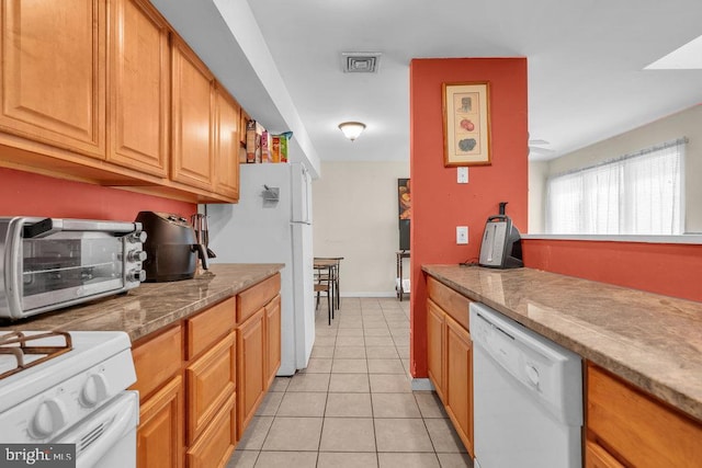 kitchen with light tile patterned flooring, a toaster, white appliances, visible vents, and light countertops