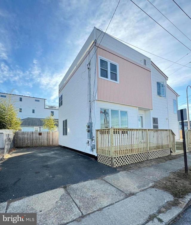 rear view of property featuring fence and a deck