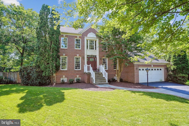 view of front of home with a front yard, brick siding, fence, and driveway