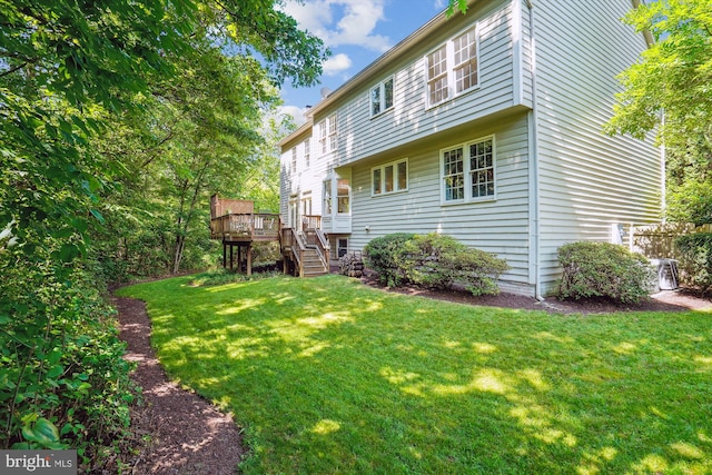 rear view of property with a yard, a wooden deck, and stairs