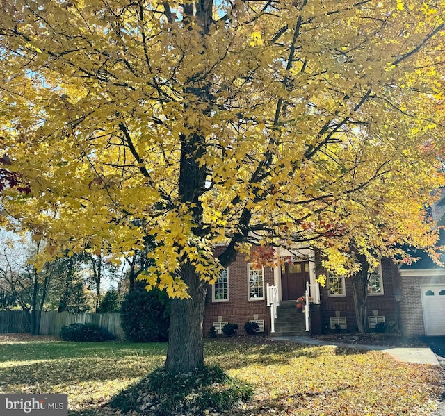 obstructed view of property with a garage, a front lawn, fence, and brick siding