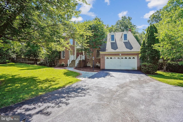 view of front of home with aphalt driveway, brick siding, an attached garage, a front yard, and fence