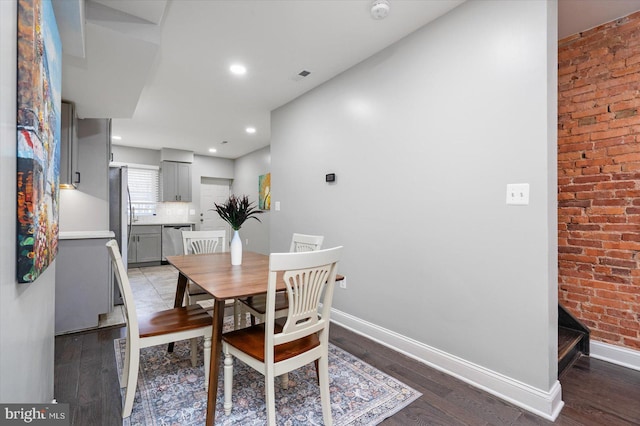 dining area featuring brick wall, dark wood-type flooring, recessed lighting, and baseboards