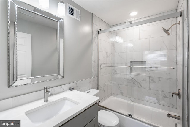 bathroom featuring visible vents, shower / bath combination with glass door, vanity, and toilet