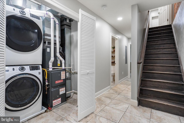 laundry area featuring recessed lighting, stacked washer / dryer, light tile patterned flooring, laundry area, and baseboards