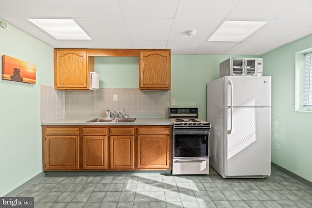 kitchen with light countertops, white appliances, a sink, and decorative backsplash