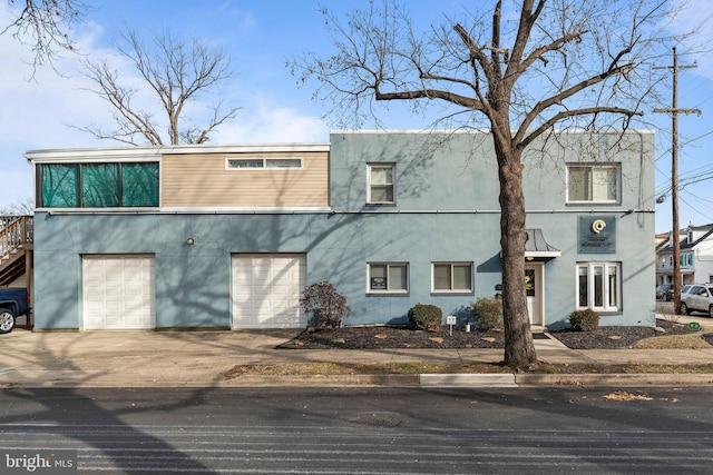 view of front of house with a garage, concrete driveway, and stucco siding