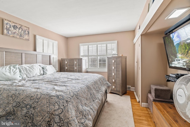 bedroom featuring light wood finished floors and baseboards