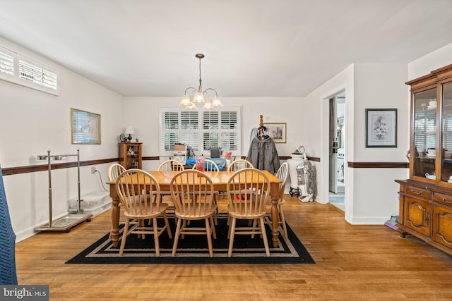 dining area featuring a notable chandelier, baseboards, and light wood-style floors