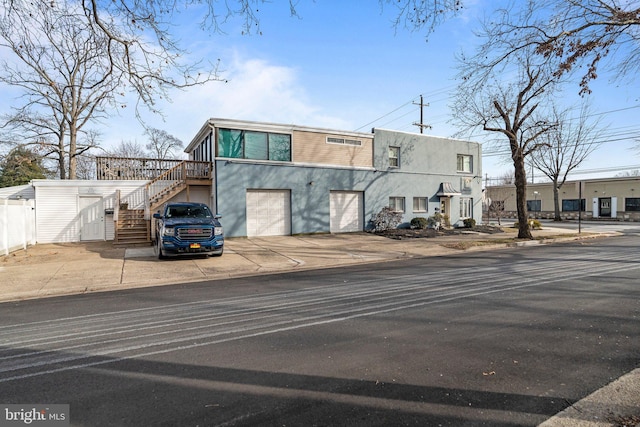 view of property featuring a garage, driveway, stairway, and stucco siding