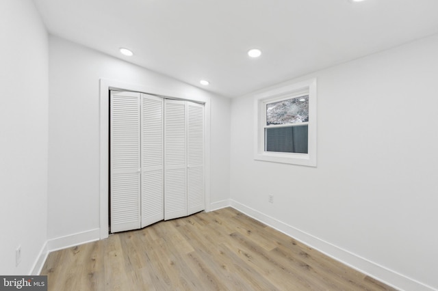 unfurnished bedroom with light wood-style floors, baseboards, a closet, and recessed lighting