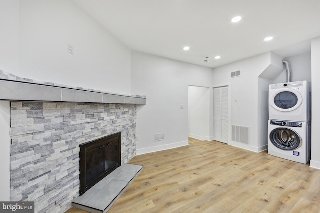 washroom featuring a stone fireplace, recessed lighting, stacked washer / dryer, visible vents, and light wood-style floors