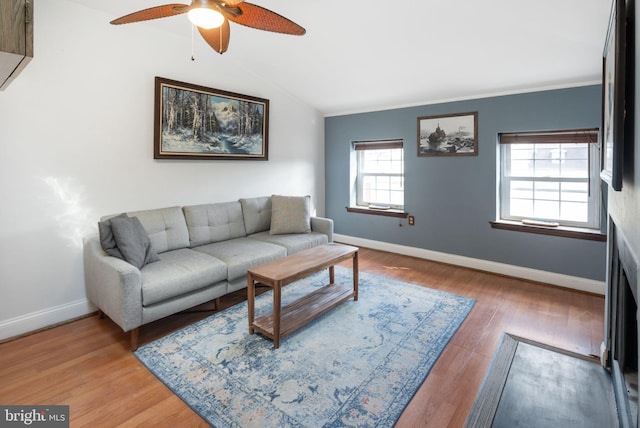 living area with ceiling fan, baseboards, vaulted ceiling, and wood finished floors