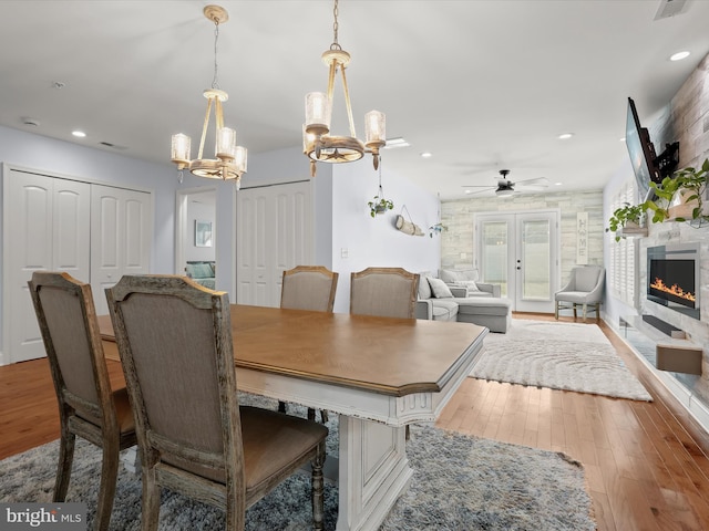 dining area with a tiled fireplace, hardwood / wood-style flooring, recessed lighting, and french doors