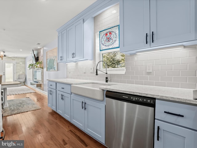 kitchen featuring dark wood-style flooring, a sink, stainless steel dishwasher, open floor plan, and backsplash