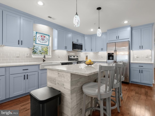 kitchen featuring visible vents, a sink, appliances with stainless steel finishes, a breakfast bar area, and dark wood-style flooring
