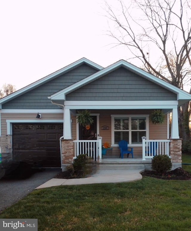 craftsman-style home featuring a porch, driveway, a front lawn, and a garage