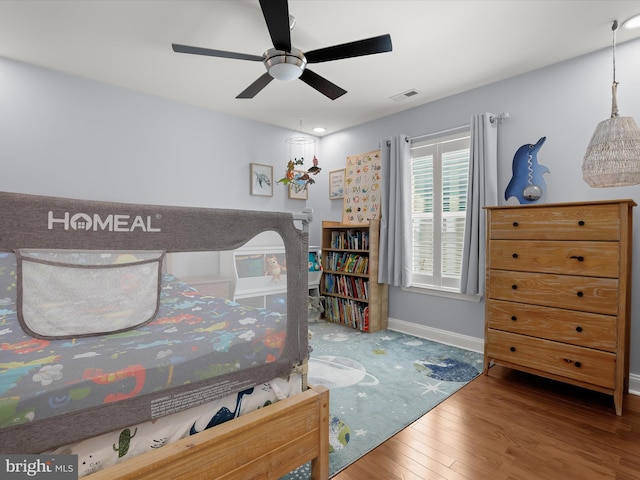 bedroom featuring visible vents, baseboards, a ceiling fan, and hardwood / wood-style flooring