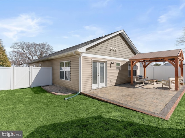 rear view of house with a gazebo, a lawn, a fenced backyard, a patio area, and a gate