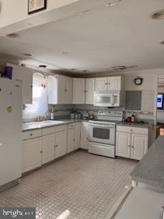 112 Mitchell St, Saint Michaels, MD 21663 - kitchen featuring dark countertops, white appliances, white cabinetry, and a sink
