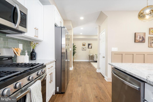 kitchen with light stone counters, appliances with stainless steel finishes, and white cabinetry