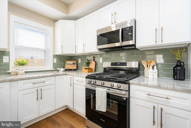 kitchen with stainless steel appliances, light wood-style flooring, backsplash, and white cabinetry