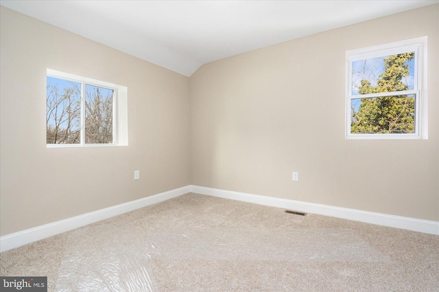 carpeted empty room featuring vaulted ceiling, visible vents, and baseboards