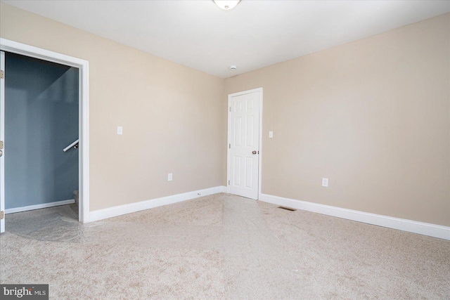 unfurnished bedroom featuring light carpet, visible vents, baseboards, a spacious closet, and a closet