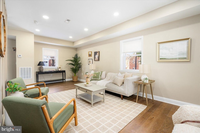 living room with recessed lighting, visible vents, baseboards, and wood finished floors