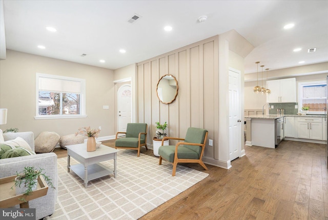 living room featuring light wood-type flooring, baseboards, visible vents, and recessed lighting