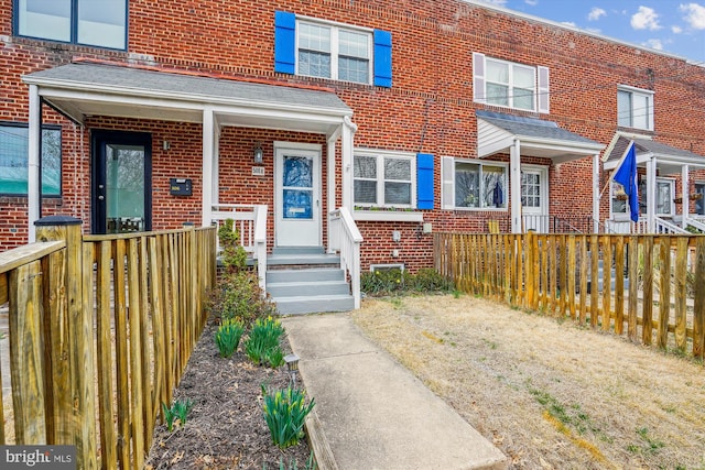 view of front facade with brick siding and fence