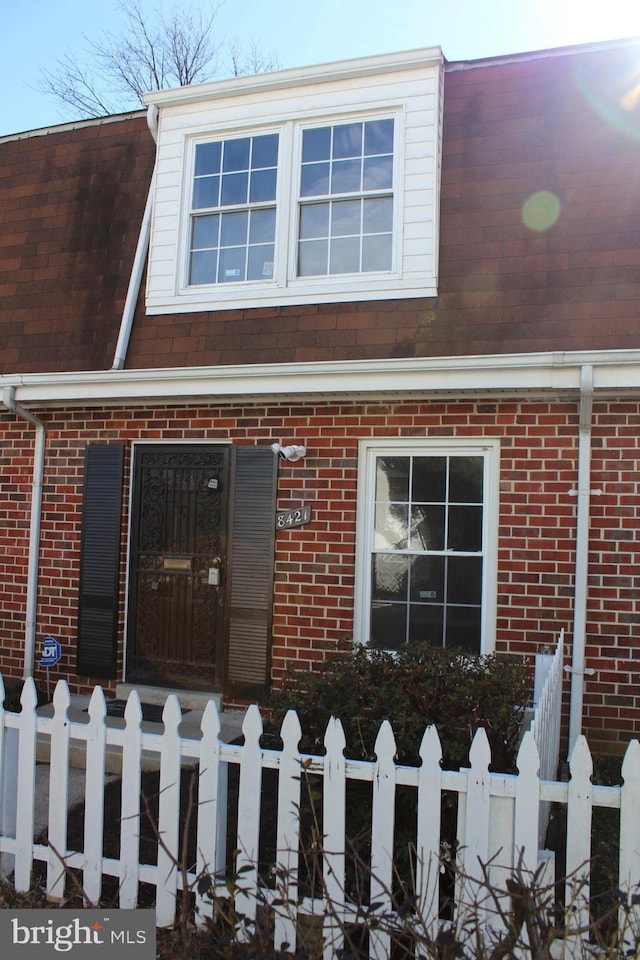 view of front of house featuring a fenced front yard, a shingled roof, and brick siding