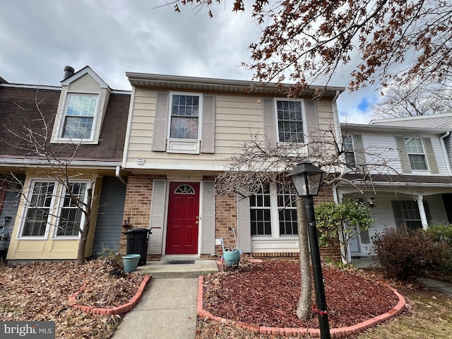 townhome / multi-family property featuring brick siding and roof with shingles