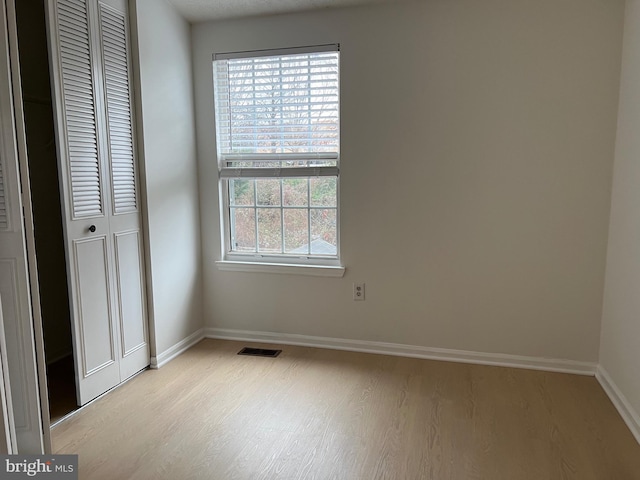 unfurnished bedroom with a closet, visible vents, light wood-style flooring, and baseboards