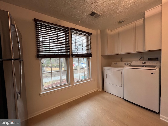 laundry room with cabinet space, visible vents, light wood-style flooring, separate washer and dryer, and baseboards