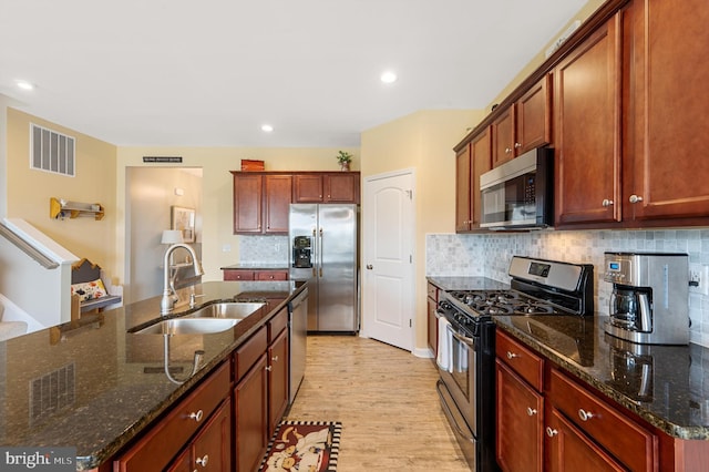 kitchen with visible vents, decorative backsplash, light wood-style flooring, appliances with stainless steel finishes, and a sink