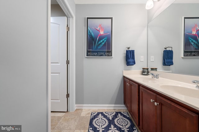 full bathroom featuring double vanity, a sink, and baseboards