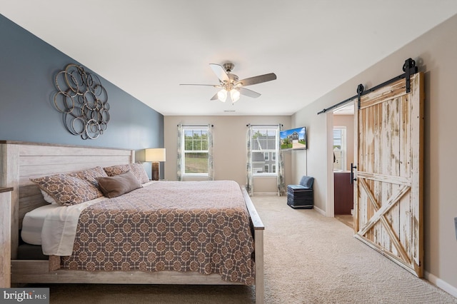 carpeted bedroom with a barn door, baseboards, and a ceiling fan