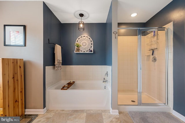 bathroom featuring a stall shower, a bath, and baseboards