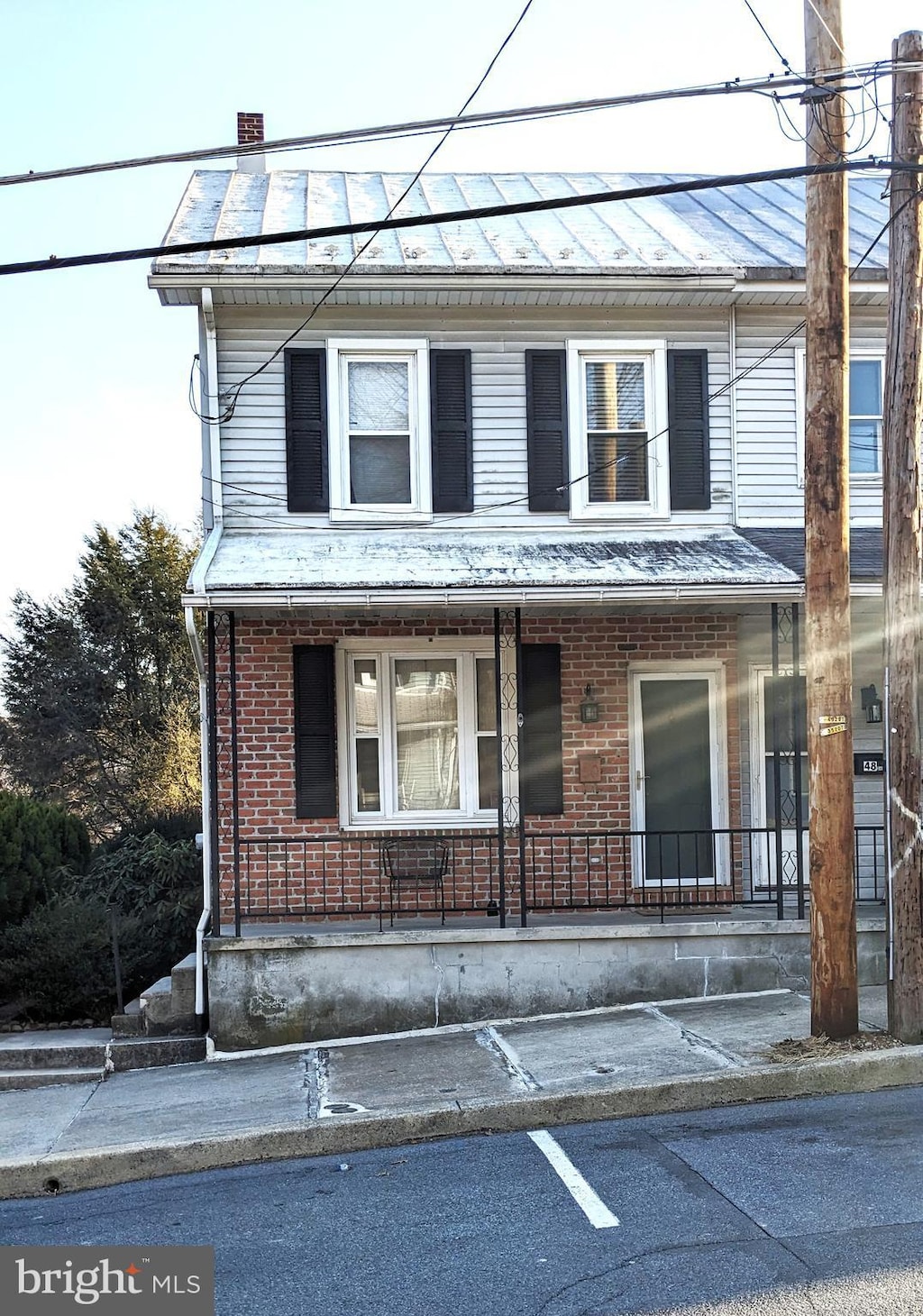 view of front of house with a chimney, a porch, and brick siding