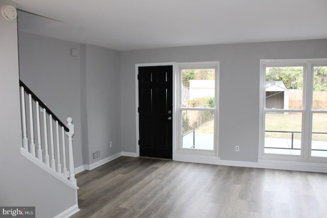 foyer featuring baseboards, visible vents, stairway, and wood finished floors