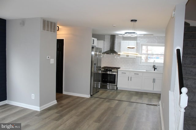 kitchen with tasteful backsplash, wall chimney exhaust hood, stainless steel appliances, white cabinetry, and a sink