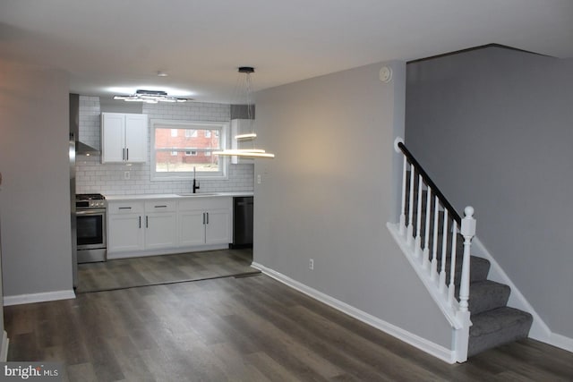 kitchen featuring dark wood finished floors, tasteful backsplash, gas stove, white cabinetry, and a sink