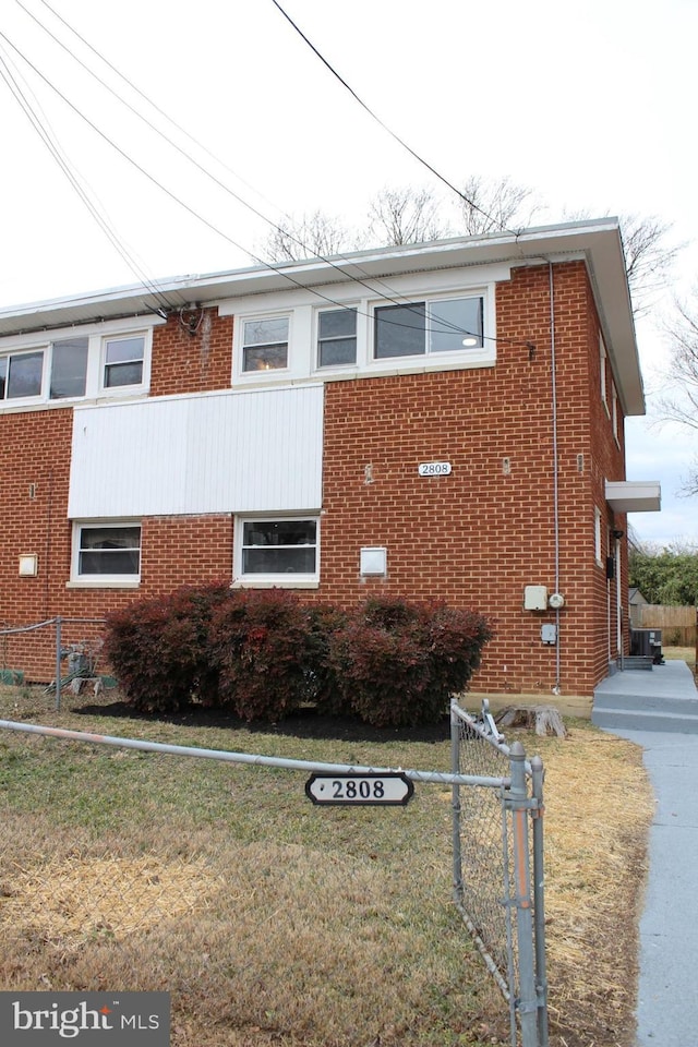 view of home's exterior with a yard, brick siding, and fence