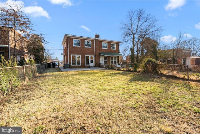 back of property with brick siding, a chimney, a lawn, cooling unit, and a fenced backyard