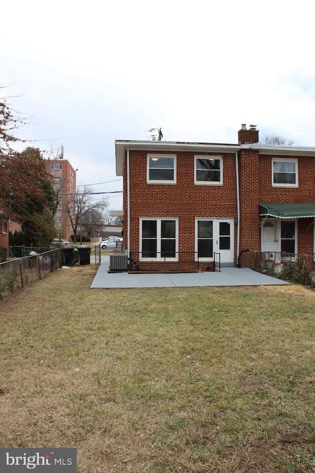 rear view of property featuring brick siding, a yard, a chimney, fence, and cooling unit