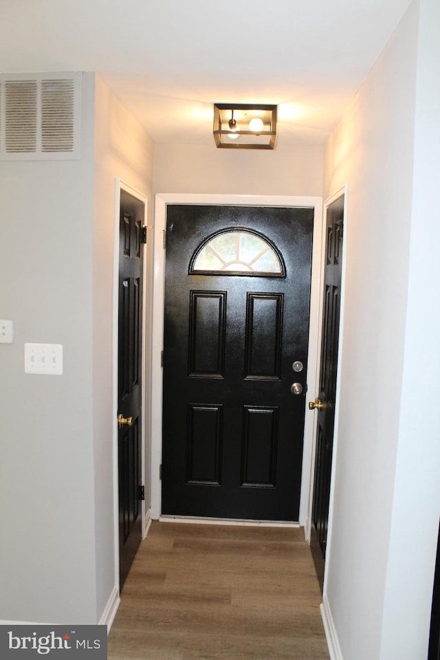 doorway featuring wood finished floors, visible vents, and baseboards