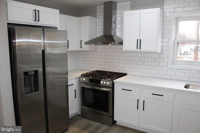 kitchen featuring white cabinets, decorative backsplash, wall chimney exhaust hood, appliances with stainless steel finishes, and light countertops