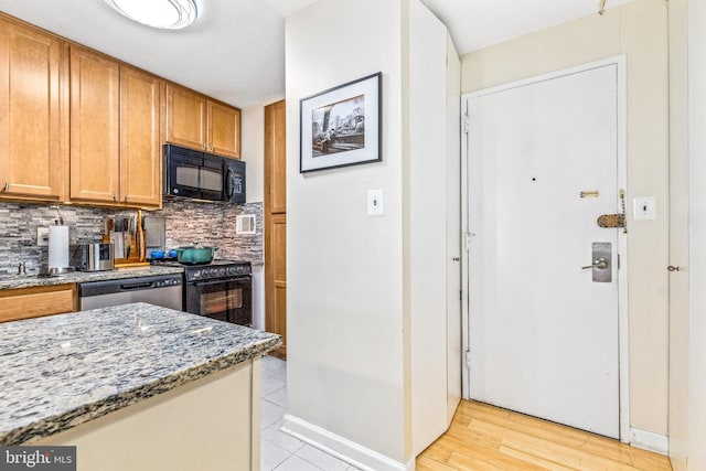 kitchen featuring stone counters, brown cabinets, backsplash, and black appliances